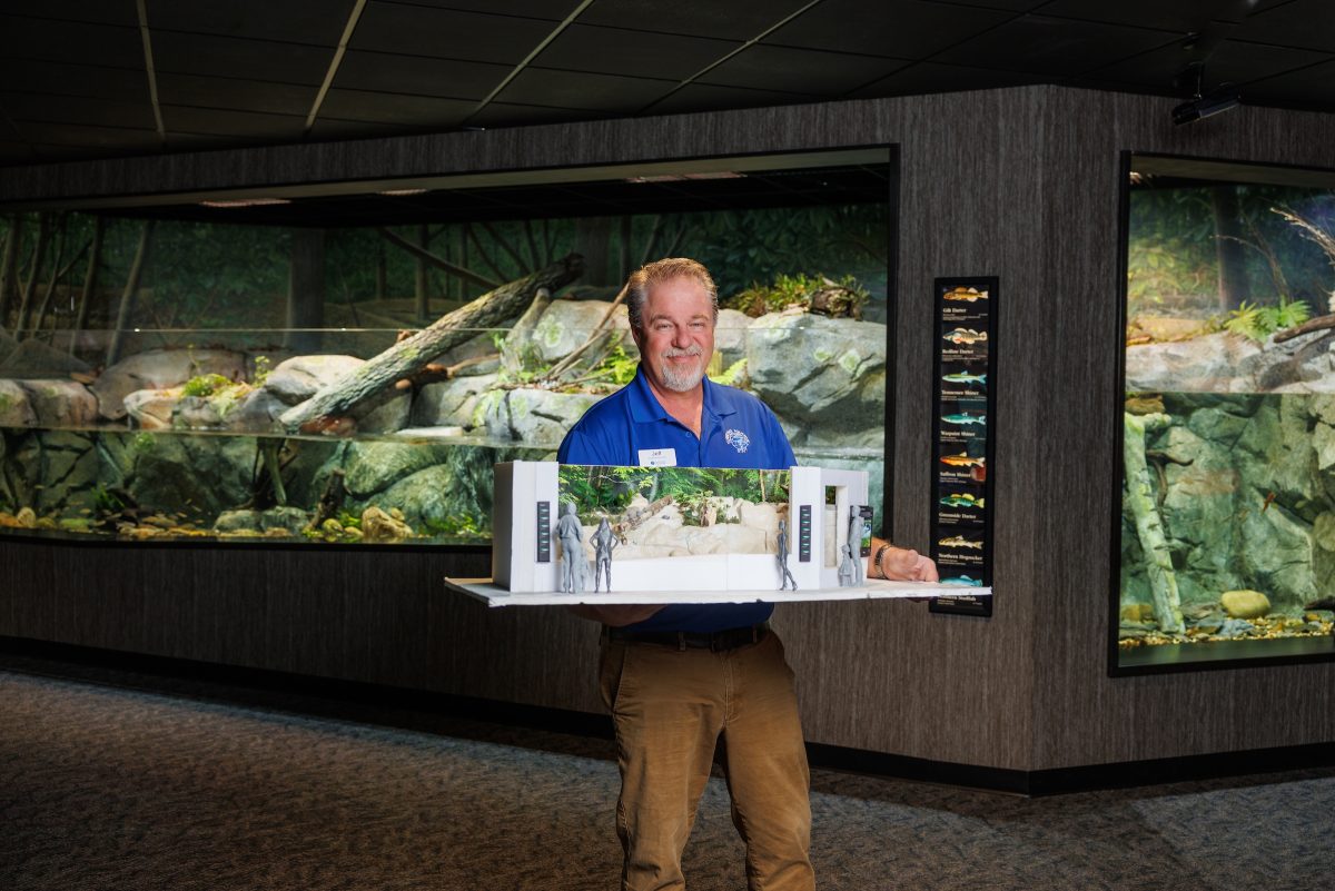 Jeff Worley holding exhibit model inside Ridges to River gallery