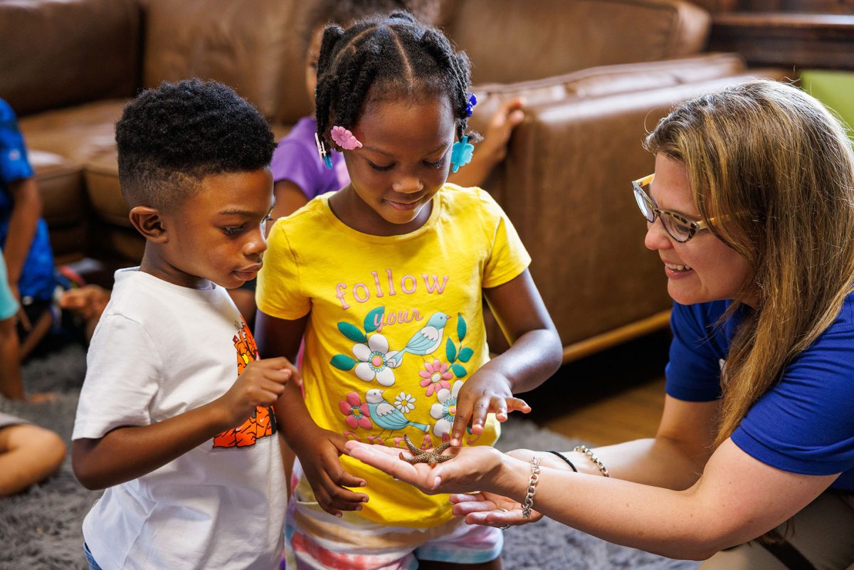 educator showing sea star to two students